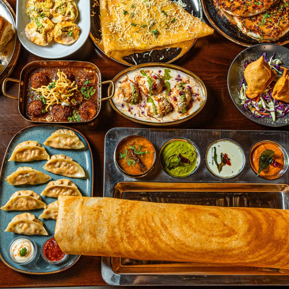 A variety of Mirch Masala Town's Indian dishes, including dosa, momos, samosas, and curries.