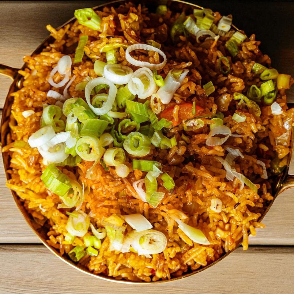 Close-up of Mirch Masala Town's Indian fried rice, garnished with fresh green and white scallions.